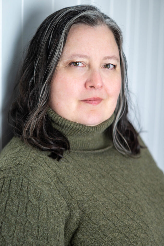 A woman with dark hair wearing a green sweater.